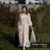 Model wearing an ivory embroidered muslin-silk 3-piece suit with pink and green floral patterns, part of Jubaida’s Collection by Pure & Luxe, standing in a natural outdoor setting.