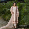 Woman wearing a blush pink embroidered muslin-silk 3-piece suit with floral detailing, holding a scalloped dupatta, standing in a garden setting.